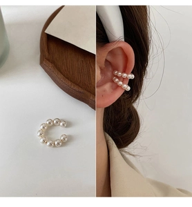 Detail of C-shaped 14k gold-plated ear cuff with small white pearls on a model