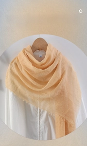 Detail of peach cotton linen scarf showing soft crinkled texture and fringe edges