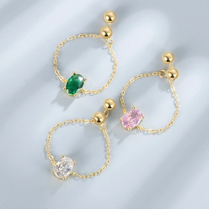 Detail of adjustable gold chain rings with oval-cut emerald, pink, and clear zircon stones