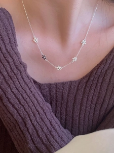Detail of delicate 925 silver necklace with small flower pendants on a model
