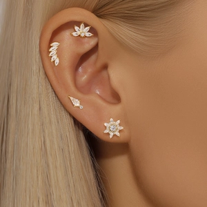 Close-up of gold geometric CZ ear piercing set on model including leaf and floral studs