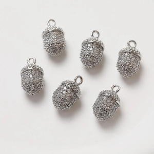 Macro detail of six silver acorn pendants with cubic zirconia inlay for DIY jewelry