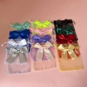 Detail view of 12 colorful organza gift bags with satin ribbons on pink background