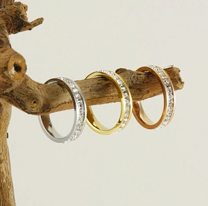 Trois bagues d'éternité en or, argent et or rose sur un support en bois naturel