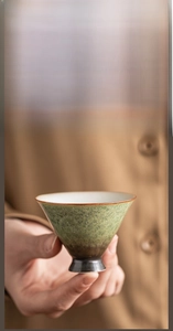 Detail of kiln-changed ceramic tea cup with emerald texture and smooth white interior