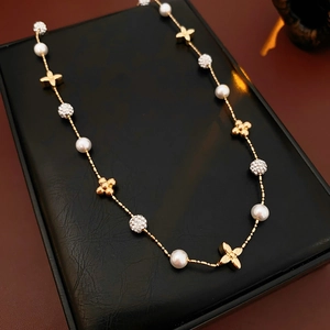 Macro view of gold flower necklace with pearls and zircon charms on black leather display