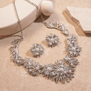Silver geometric flower jewelry set with pearls on artistic stone display