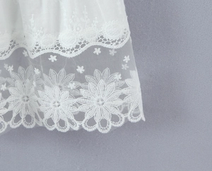 Détail de la broderie en dentelle blanche et du mesh transparent sur la jupe