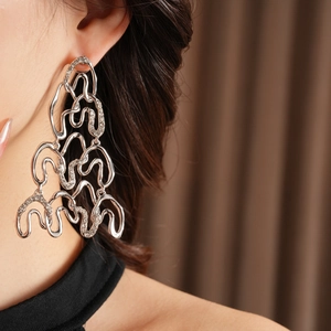 Close-up of long silver wave-shaped earrings with fine stones on a model