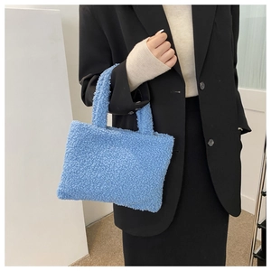 Blue fuzzy plush handbag for women styled with a black blazer in a modern indoor setting