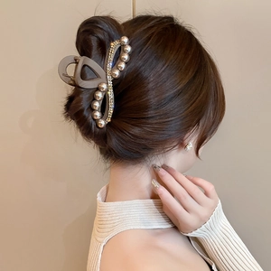 Elegante pinza per capelli in acrilico marrone con perle e strass su una modella