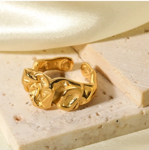 Detailed view of golden irregular lava texture ring on beige stone with silk backdrop