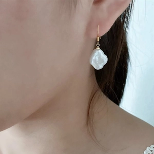 Baroque pearl clover earrings with gold ear hooks worn elegantly on a model's ear