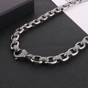 Macro shot of 12mm silver punk cross chain necklace with Greek key pattern and textured clasp