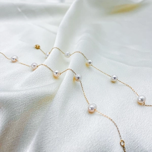 Close-up of elegant station gold chain bracelet with pearls on a white silk background