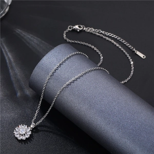 Close-up of silver snowflake necklace featuring zircon cluster pendant on grey stand