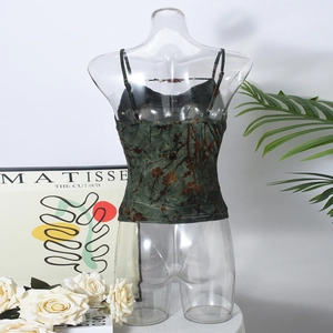Detail eines grünen Samt-Camisoles mit verstellbaren Kreuzgurten und Blumenmuster