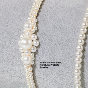 Detailed close-up of handmade white faux pearl cluster hairband on grey velvet surface