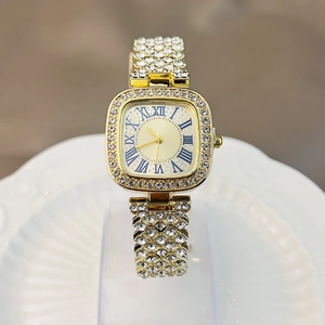 Detail of a gold square watch featuring a diamond-set bezel and blue Roman numerals dial