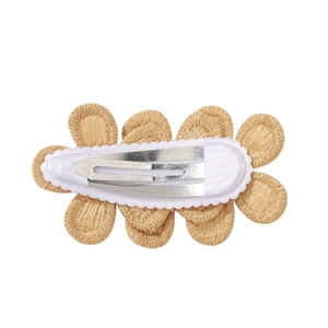 Détail du clip métallique et de la base en tissu blanc au dos de la barrette fleur