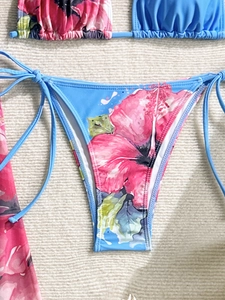 Detail of blue bikini bottoms with pink floral print and adjustable side ties on white fur