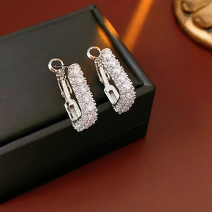 Gros plan de boucles d'oreilles en argent en forme de U pavées de zircons sur un écrin noir