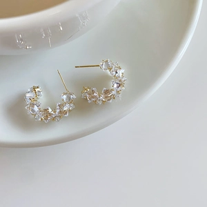 Macro view of C-shaped stud earrings with gold plating and paved sparkling zircons