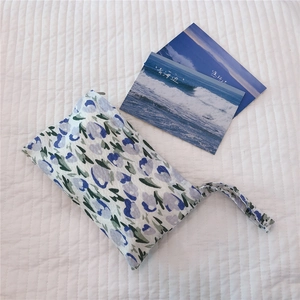 Close-up of mini floral cotton handbag with zipper and wrist strap on white background