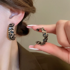 Close-up of leopard print resin earrings worn by a model for a chic fall fashion style