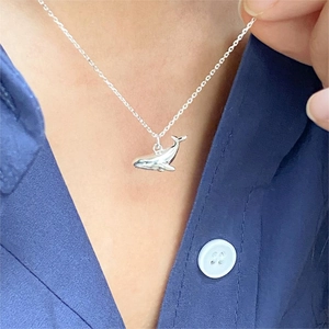Minimalist 925 sterling silver whale pendant necklace worn on neck with navy shirt