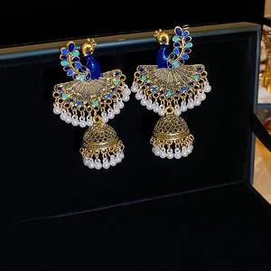 Detailed close-up of peacock enamel tassel earrings with white pearls on a black box