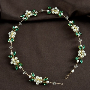 Detail of bridal hair vine with white pearls and green crystal leaves on golden wire