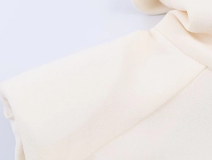Detailed close-up showing refined shoulder seam and cream fabric texture of the blouse