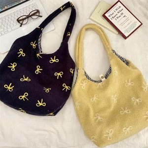 Détail de sacs fourre-tout en peluche avec broderie de nœuds et doublure à carreaux