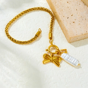 Bracelet à chaîne dorée avec pendentif nœud et perle nacrée sur un décor en pierre