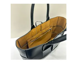 Interior view of black woven leather tote bag with yellow suede lining and pocket
