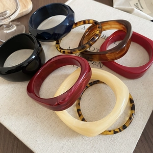 Macro shot of colorful acrylic geometric bangles featuring leopard print and solid resin textures
