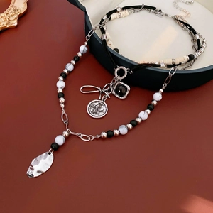 Detail view of multi-layer beaded necklace with vintage pendants in a green jewelry box