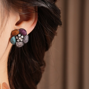 Close-up of vintage floral earrings with colorful zircons on a dark metal setting