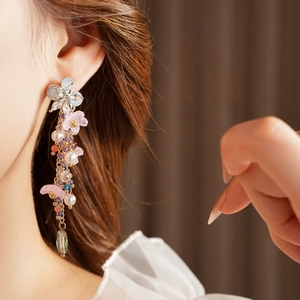 Dettaglio di orecchini vintage a fiore con perle e cristalli indossati da modella