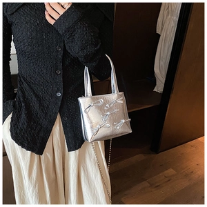 Detail view of silver mini square bag with metallic texture and 3D bow decorations