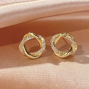 Close-up of gold Mobius hoop earrings featuring polished metal and sparkling zircon stones