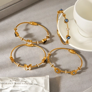 Gold cable wire bracelets with evil eye, heart and butterfly charms in 18k gold plating