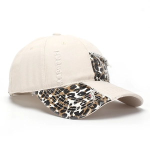 Detailed close-up of leopard print patchwork and distressed ripped denim on baseball cap