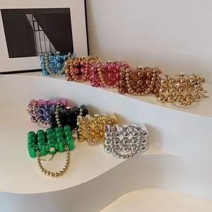 Mini acrylic spherical clutch bags in metallic candy colors with chain handles on white steps
