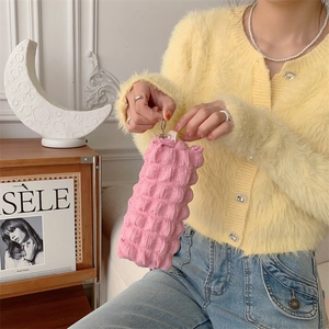 Close-up of pink bubble-textured pouch with metal zipper and ring held by a person