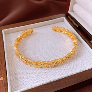 Detail of 18k gold-plated enamel flower bangle displayed in a white wooden jewelry box