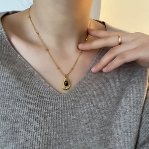 Collana con ciondolo occhio di tigre e anello d'oro su maglione lavorato a maglia