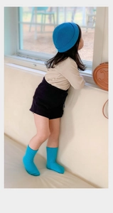 Detailed view of child wearing bright blue knitted beanie hat and matching crew socks