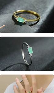Macro detail of rectangle emerald ring with side diamonds on dark textured background